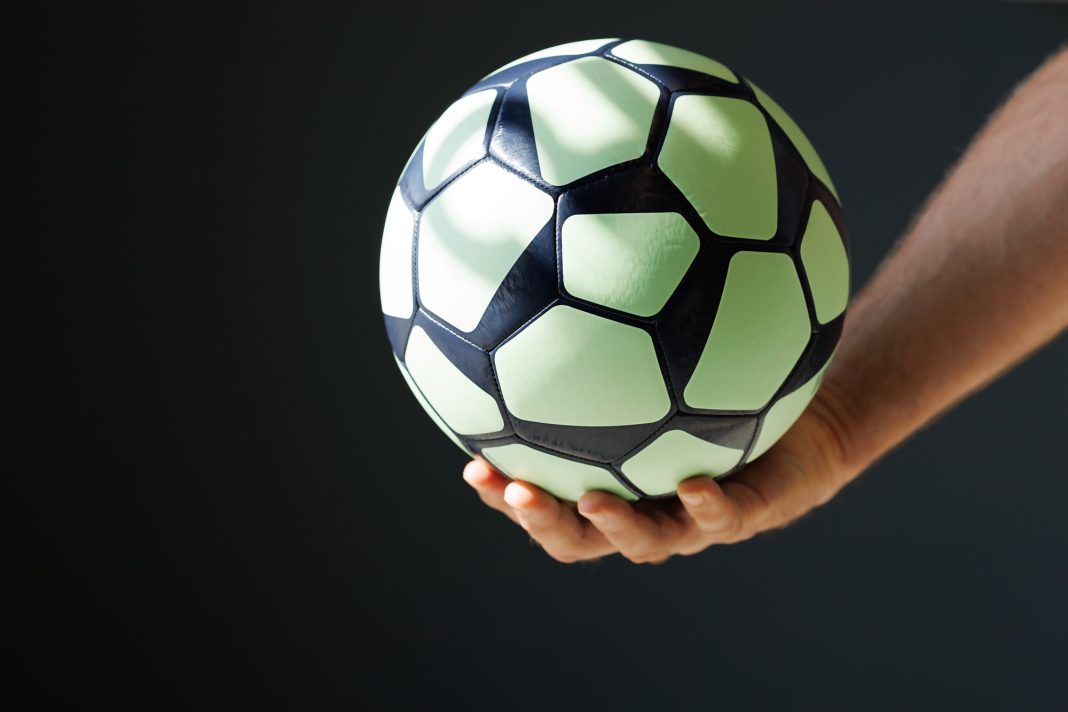 green black ball for handball in the athlete's hand on a black background
