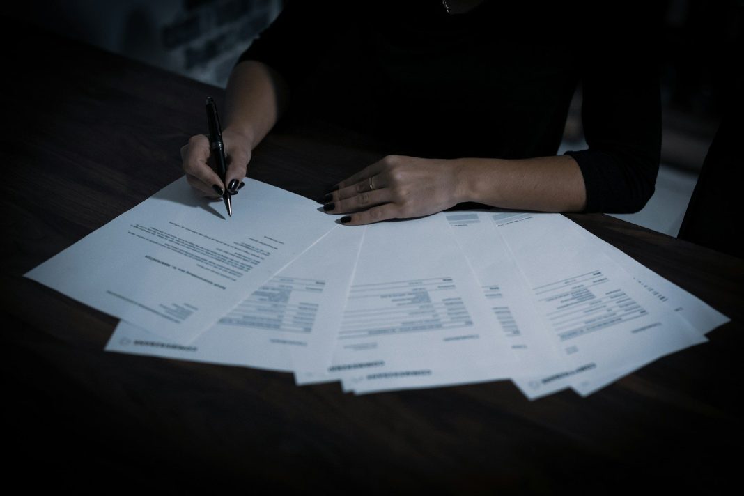 Javni natječaj za prodaju nekretnina u Sisku a woman sitting at a table with lots of papers